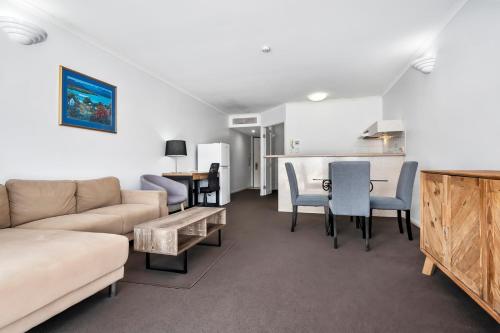 a living room with a couch and a table and chairs at Il Centro Apartment Hotel in Cairns