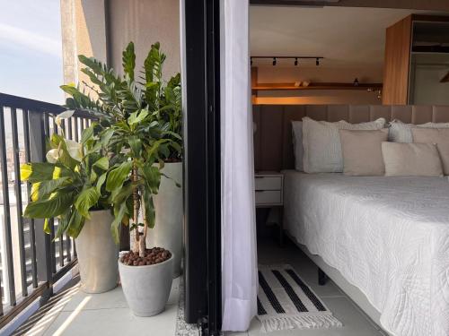 Luxuoso Studio no Rio com Vista para o Cristo في ريو دي جانيرو: غرفة نوم بها سرير ونباتين في أصيص على شرفة
