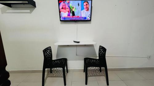 Quero mais arraial suites في أرايال دو كابو: طاولة مع كرسيين وتلفزيون على الحائط