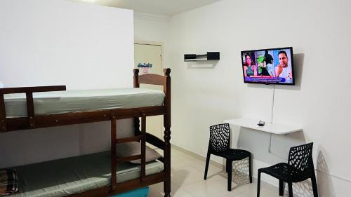 Quero mais arraial suites في أرايال دو كابو: غرفة نوم بها سرير بطابقين مع كرسيين ومكتب