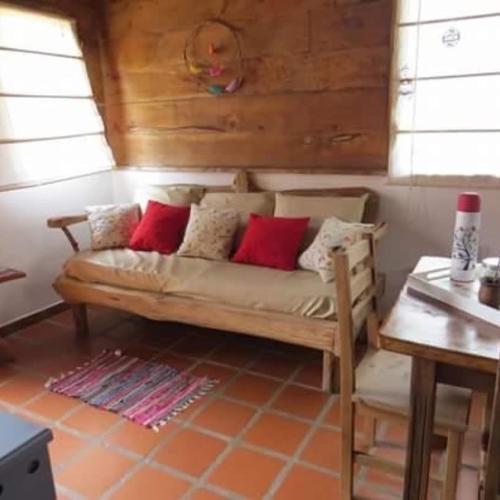 un sofá con almohadas rojas en una habitación en Cabañas Agua de Piedra, en Villa Giardino