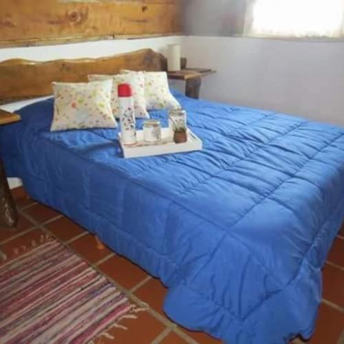 Una cama azul con una bandeja con velas encima. en Cabañas Agua de Piedra, en Villa Giardino