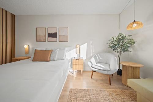 a white bedroom with a bed and a chair at Cozy Creek Den - Updated Nov 2025 in Whistler