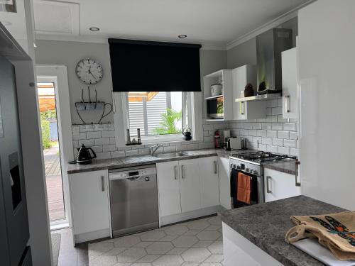 a kitchen with white cabinets and a clock on the wall at Unique Beachside Home in Eastbourne in Lower Hutt
