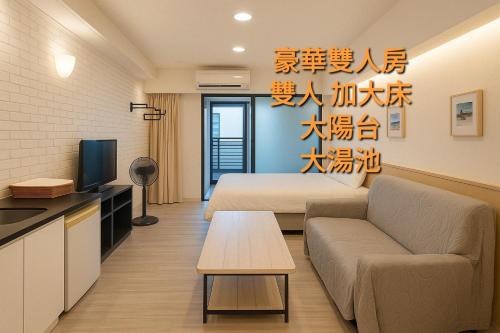 a room with a bed and a couch and a tv at Golden Wing樓中樓溫泉宿 in Jiaoxi