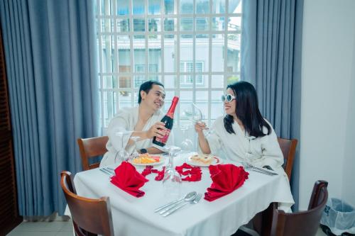 a man and woman sitting at a table with a bottle of wine at White Corner Hotel in Phnom Penh