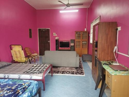 Una habitación con paredes rosas y una cama y un televisor. en The Scholar's Den Homestay, en Kampong Bukit Kechil