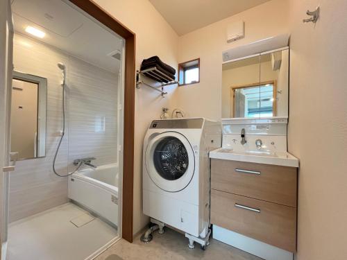 a bathroom with a washing machine and a sink at Hakuba Icicle House in Hakuba