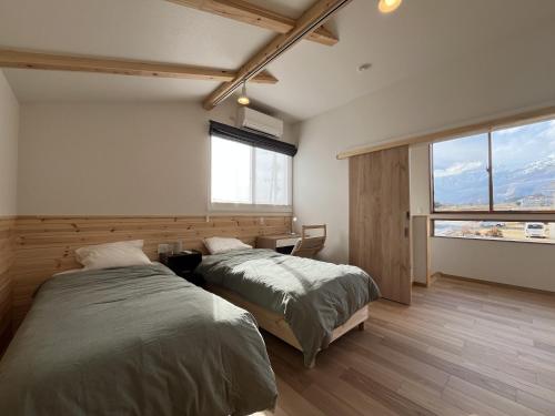 a bedroom with two beds and a window at Hakuba Icicle House in Hakuba