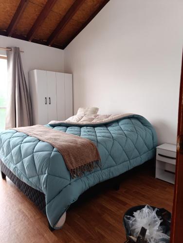 Un dormitorio con una cama con un edredón verde. en Cabaña La Sonrisa, en Maldonado