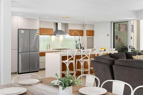 a kitchen and living room with a couch and a table at Saltbreeze - Laidback Poolside Living in Twin Waters