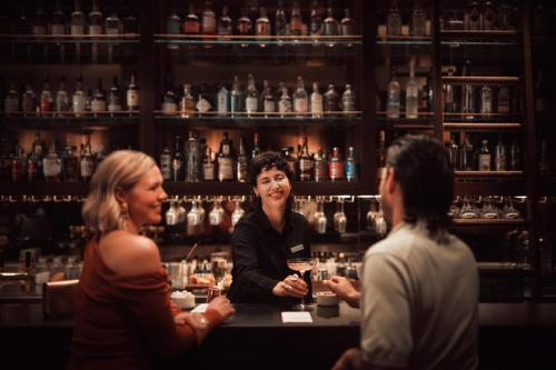 a group of people sitting at a bar at Next Hotel Melbourne, Curio Collection by Hilton in Melbourne