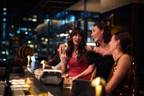 a group of women sitting at a bar at night at Next Hotel Melbourne, Curio Collection by Hilton in Melbourne