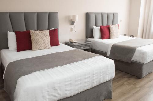 two beds in a hotel room with red pillows at Hotel Santander Plaza in Guatemala