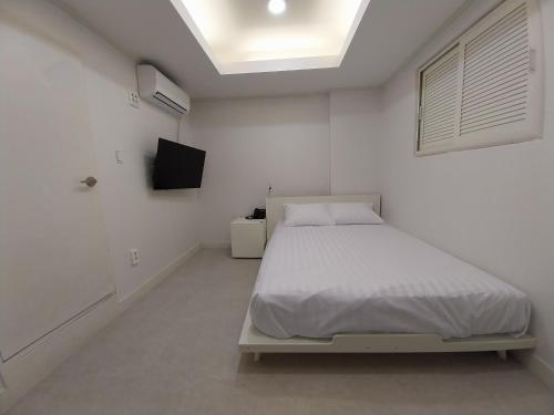 a white bedroom with a bed and a television at GaGa Hotel dongdaemun in Seoul