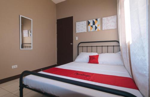 a bedroom with a bed with a red pillow on it at RedDoorz at Aurea Apartelle in Iloilo City