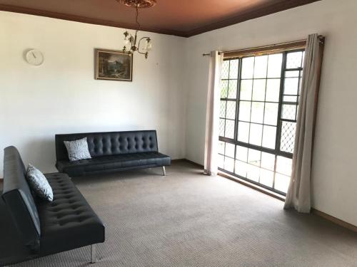 a living room with a black couch and a window at Relaxing Vintage Cottage in Corrimal
