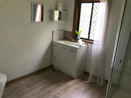 een badkamer met een wastafel en een raam bij Relaxing Vintage Cottage in Corrimal