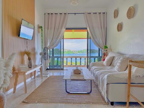 a living room with a couch and a large window at Sea Dreamer Ao Yon Beach House in Ban Ao Makham