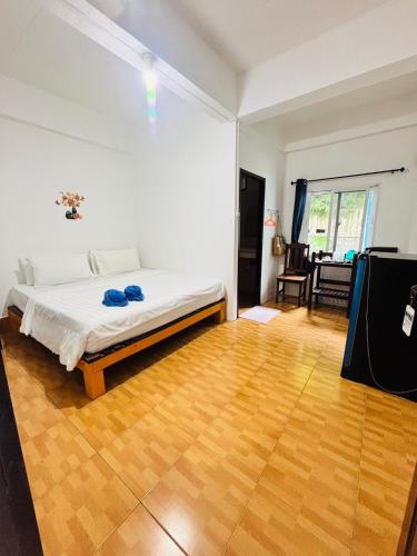 a white bedroom with a bed and a wooden floor at Miss Hong House in Ko Samed