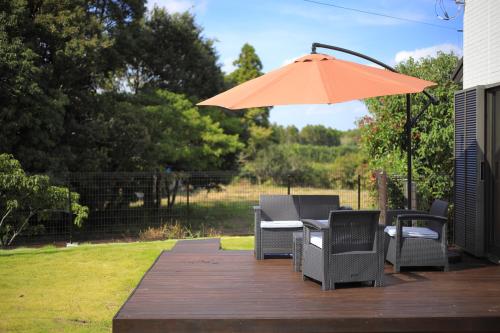 a patio with a table and chairs and an umbrella at サウナ,ドッグラン付き施設 "ガーデンハウス九十九里" -Garden House KUJUKURI in Miyamae