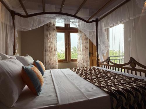 a bedroom with a canopy bed with a window at Whispering Wave Tangalle in Tangalle