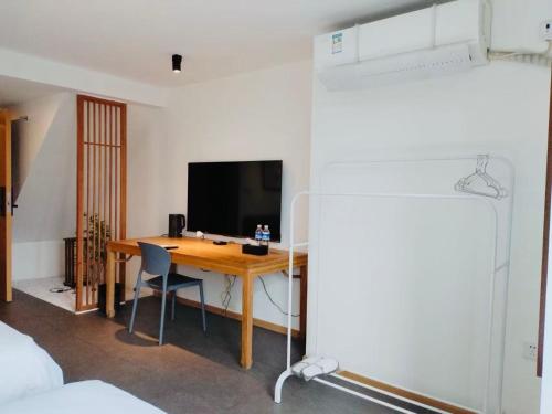 a room with a desk with a television and a bed at Chongqing Justom Family Serviced Apartments 4 in Chongqing