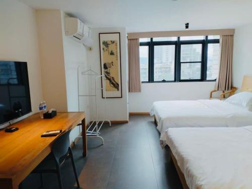 a room with two beds and a desk and a television at Chongqing Justom Family Serviced Apartments 4 in Chongqing