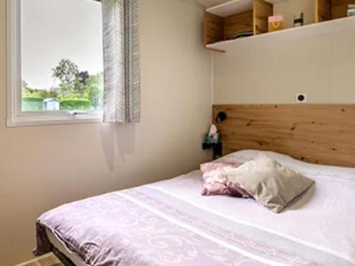 a bedroom with a bed with a pillow and a window at Mobil-home à Pordic 4 pers. avec Terrasse - API-1-52-1204 in Pordic