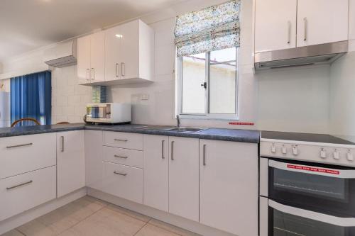 a white kitchen with white cabinets and a window at Blueys Beach Villa Manyana 14 in Blueys Beach