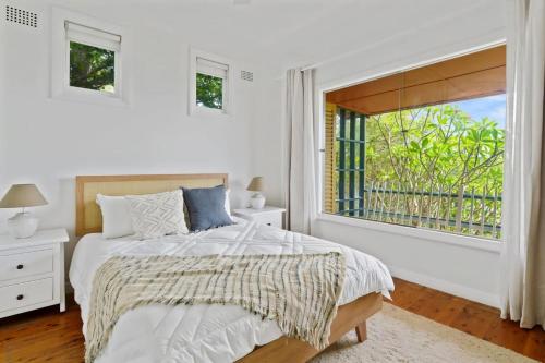 Hilltop Hideaway Family Escape في Merewether: غرفة نوم بيضاء مع سرير ونافذة