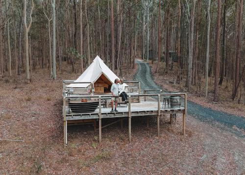 a man sitting on a dock with a tent at Kookaburra Ridge in Wyee