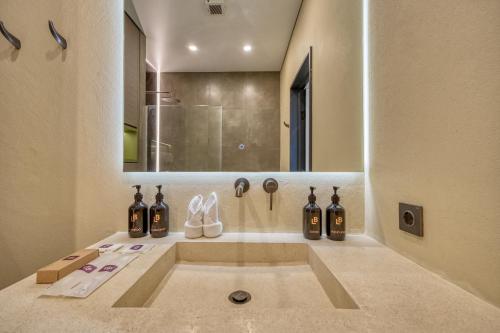 un bagno con un lavandino con bottiglie e scarpe di XO Canggu adults only a Canggu