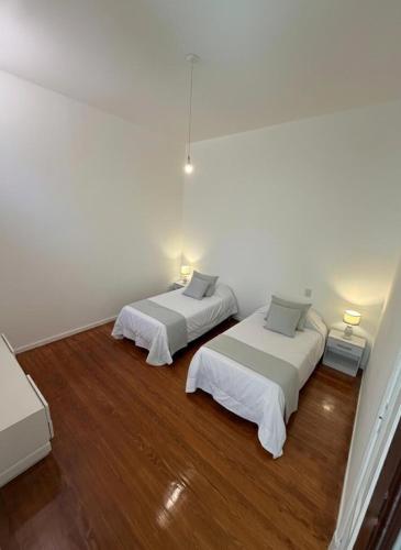 two beds in a white room with wood floors at The Marseille Oasis in La Porteña