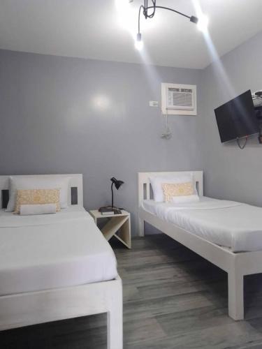 a bedroom with two beds and a tv on the wall at Angel's Bed and Breakfast Sipalay in Sipalay