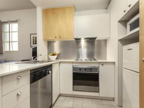 a kitchen with white cabinets and a stove top oven at Melbourne CBD Central Apartment Hotel Official in Melbourne