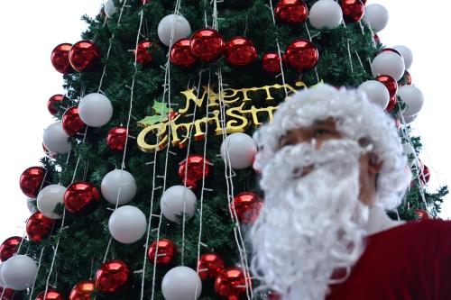 a man wearing a santa hat in front of a christmas tree at HUALUXE Sanya Yalong Bay Resort in Sanya