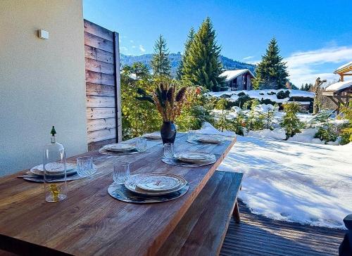 a wooden table with plates and glasses on a patio at Les Chamois D’Arbois, Mont D’Arbois, Megève in Megève