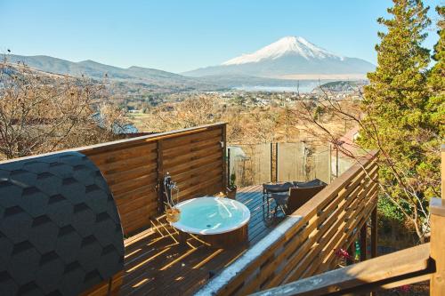 a bath tub on a deck with a mountain in the background at プライベートリゾート星池 in Yamanakako