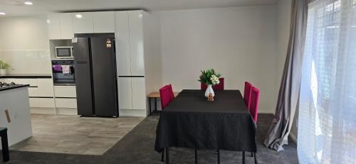 a black table with red chairs and a black refrigerator at Baden Lodge Motel - PRIVATE SPA Bath in Rotorua