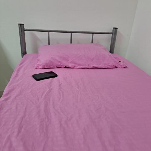 a bed with a pink blanket and a cell phone on it at New mohastel in Muscat