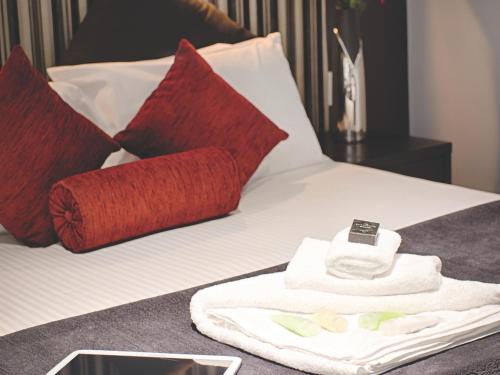 a bed with red and white pillows and a towel at Richmond Central Apartments in Melbourne