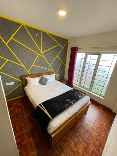 a bedroom with a bed with a yellow and gray wall at Ooty Dream Weaver cottage in Ooty