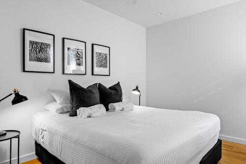 Privately Managed Golf View - Bangalay Villas في Shoalhaven Heads: غرفة نوم بيضاء مع سرير كبير مع وسائد سوداء