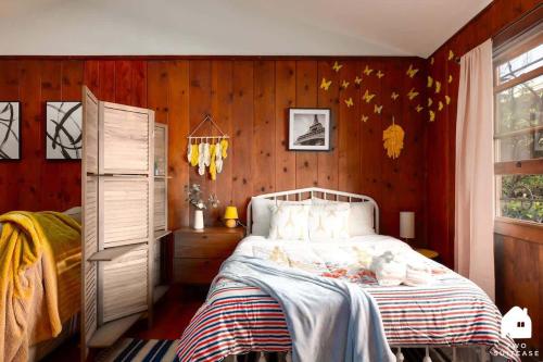 a bedroom with a bed with wooden walls and a window at Charming Garden Cottage & Walk to UC & BART & Parking in Berkeley