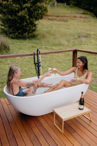 two women sitting in a bath tub on a deck at Tiny Oscar in Robertson