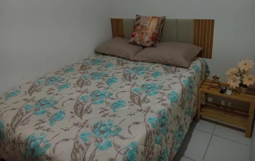 a bed with a blanket with blue flowers on it at Flat Paz & Relax Monte Castelo 1809 in Sairé