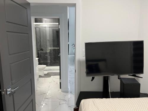 a bedroom with a flat screen tv and a bathroom at Private room with full washroom in Edmonton