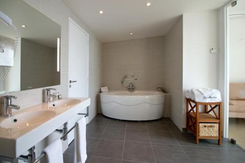 a bathroom with two sinks and a bath tub at Hôtel La Marine in Barneville-Carteret