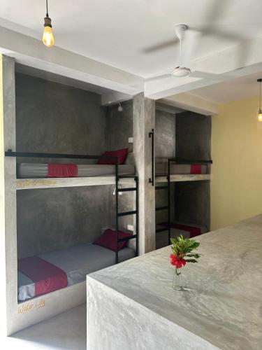 a room with three bunk beds and a table with a flower at Pranaya Hiriketiya in Hiriketiya